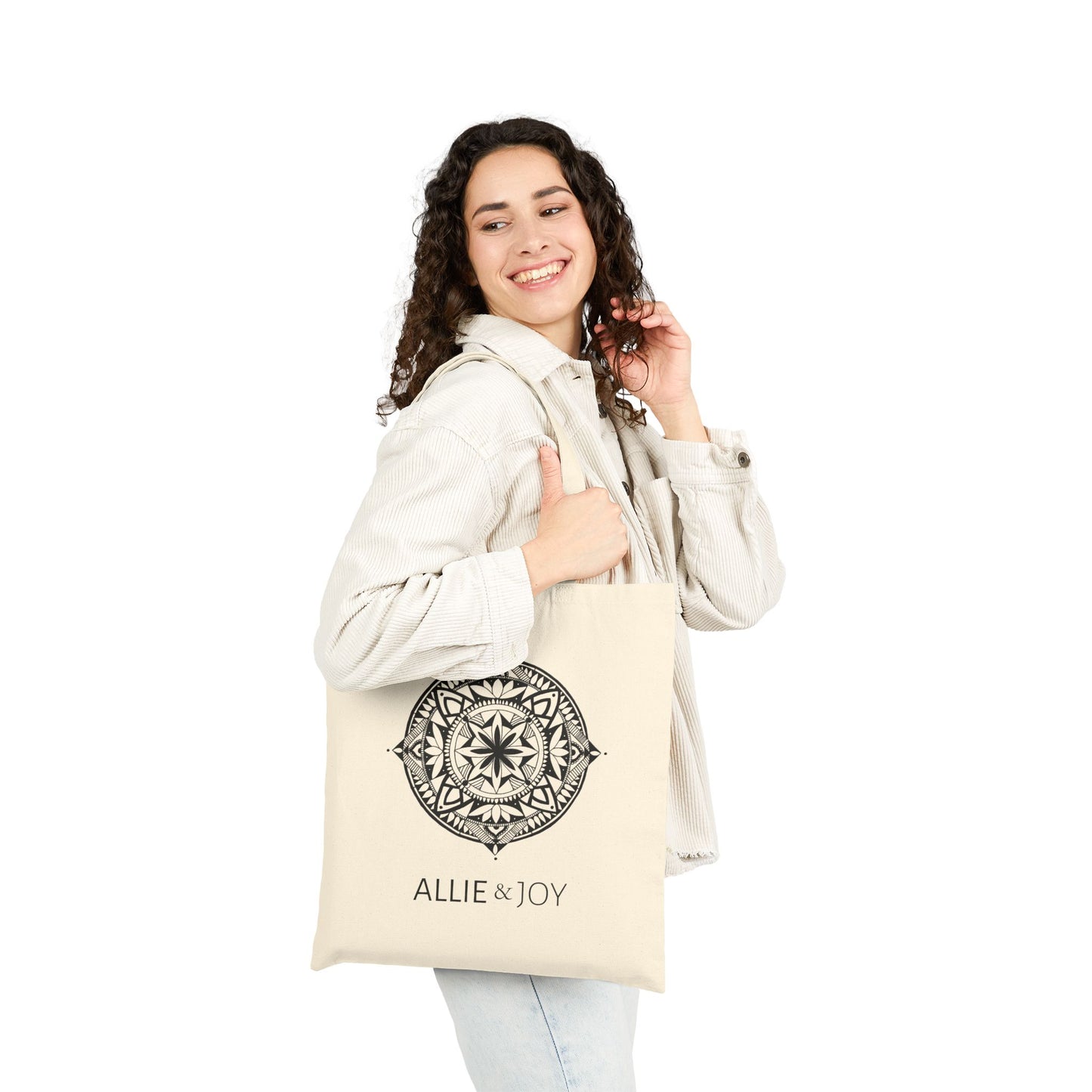 Woman holding a beige tote bag with mandala pattern and Allie & Joy logo on a white background